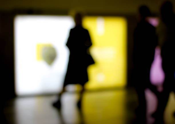 Abstract blurry image of a subway platform with human silhouettes.