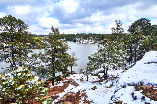 Paisaje en invierno, bosque con nieve y pinos verdes, cielo con nubes y lago en medio del bosque en el lago arareco de Creel Chihuahua