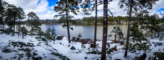 Lago en invierno con nieve entre los pinos, bosque nevado y lago con reflejos, cielo con nubes, lago arareco de la sierra tarahumara en creel Chihuahua