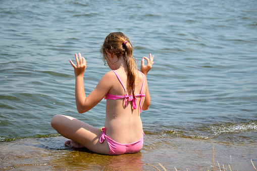 young beautiful girl with good posture, doing yoga on the seashore on a clear sunny day. healthy lifestyle, unity with nature, cleansing of the spirit and body