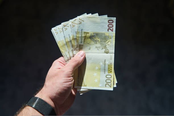 istock Euro bills in a man's hand isolated on a black background 1434529020