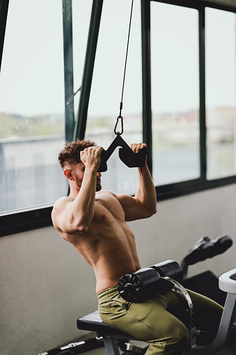 side view of a man exercising on a cable cross machine