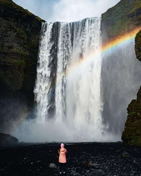 istock Vertical shot of a little girl looking at a waterfall flowing down from cliffs 1434531175