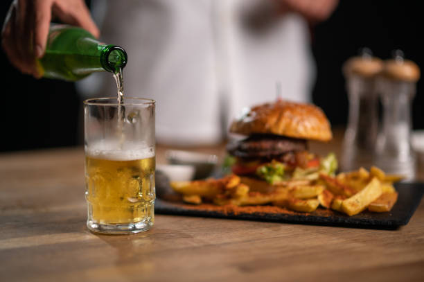 Pouting beer into glass with burgers stock photo
