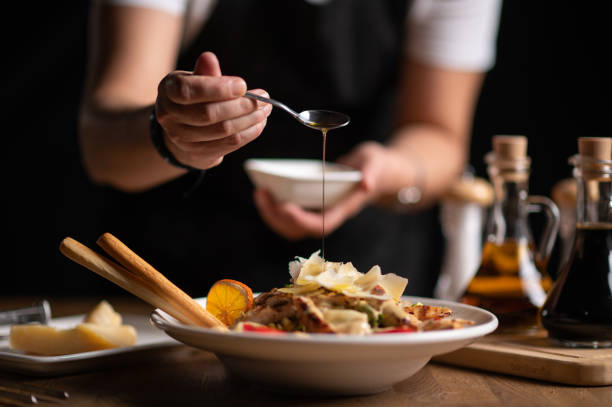 szef kuchni nalewająca sos na sałatkę - preparing food indoors horizontal close up zdjęcia i obrazy z banku zdjęć