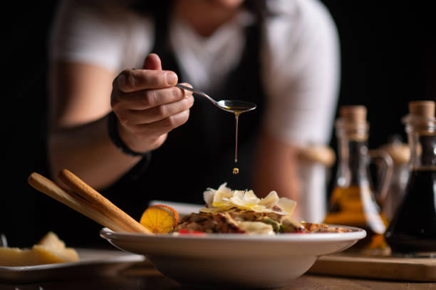 eine köchin gießt soße auf salat - serving food restaurant chicken stock-fotos und bilder