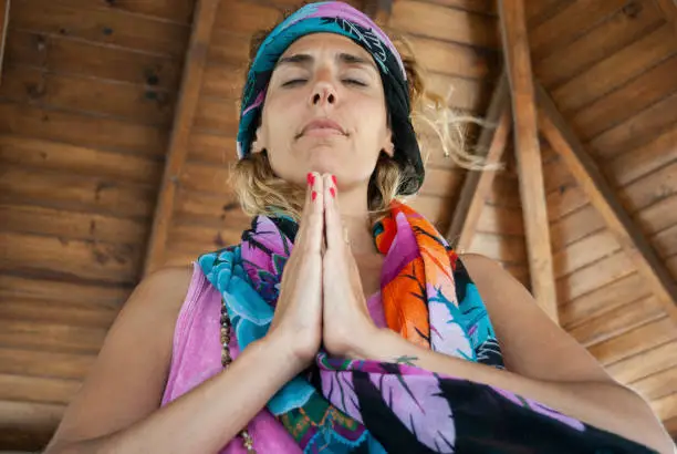 Low angle view of a woman clasping hands and wearing a bandana while meditating