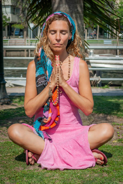 istock Young woman sitting cross-legged while meditating with her hands clasped. 1434546494