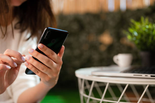istock Woman hand using a smart phone and typing a laptop close up with. selective focus. 1434548657