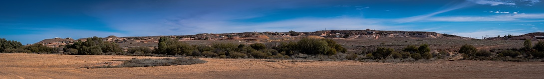 A panoramic shot of deserted land with a town in the distance, Coober Pedy, South Australia