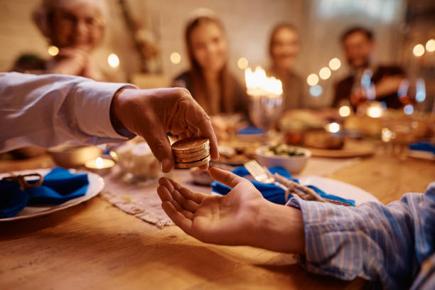 close up of jewish boy receiving hanukkah gelt from his grandfather. - gelt imagens e fotografias de stock