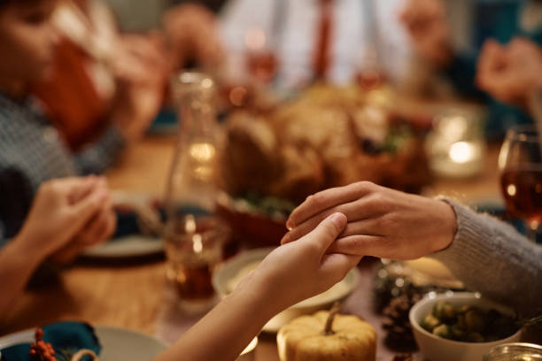 primer plano de madre e hija tomadas de la mano durante la oración familiar en acción de gracias en la mesa del comedor. - family thanksgiving dinner praying fotografías e imágenes de stock