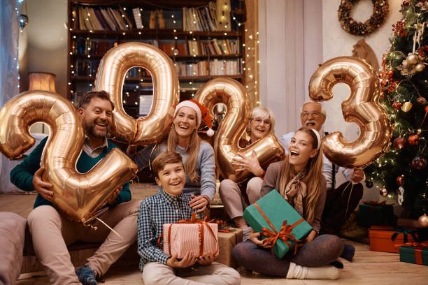 Portrait of happy extended family having fun on New Year's day at home and looking at camera. Joyful multigeneration family having fun while celebrating New Year together at home and looking at camera. family christmas party stock pictures, royalty-free photos & images