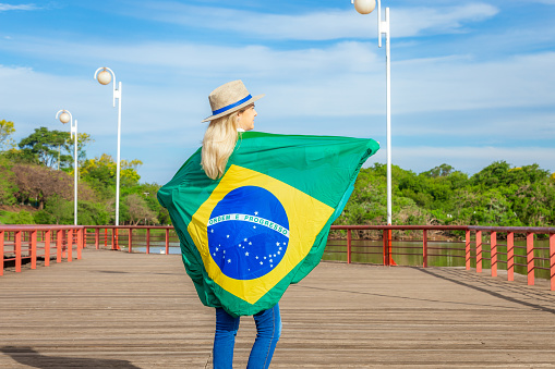 Woman wrapped in a brazilian flag wearing hat and jeans. Agribusiness woman.