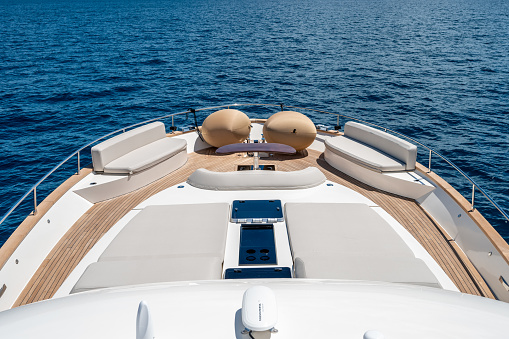 High angle view of front deck of impressive yacht. Rippled sea surface in background. Luxury vacation at sea.