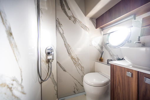 Beautiful bathroom on impressive yacht. Walls covered with white marble stone. Luxury vacation at sea.