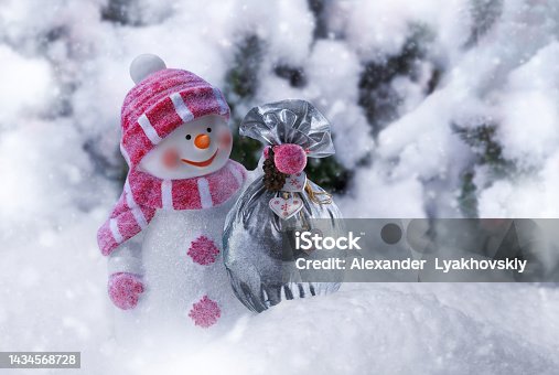 istock Happy snowman holds a bag with Christmas presents in winter snowy forest 1434568728
