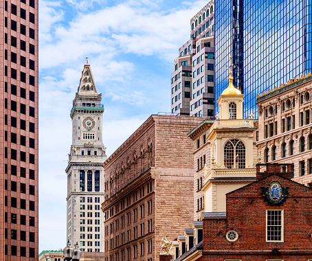 Boston, Massachusetts, USA - March 20, 2022: Skyline of historic and modern buildings in downtown Boston. The Old State House (c. 1713) in the foreground. It is one of the oldest public buildings in the United States. It is a landmark on Boston's Freedom Trail. The Custom House Tower (c. 1913) is in the background. The building is part of the Custom House District, which was added to the National Register of Historic Places in 1973.