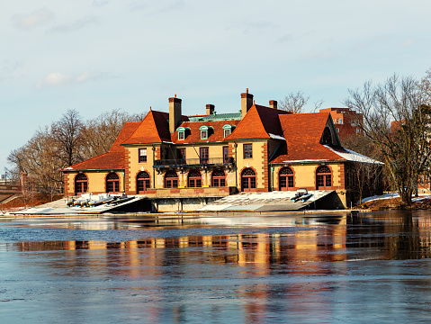 Cambridge, Massachusetts, USA - February 16, 2022: Harvard University's Weld Boathouse on the Charles River. Built in 1906, it is currently home to crews of Harvard's Varsity womens rowing program.