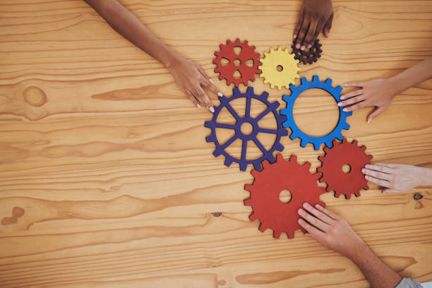 istock Success, collaboration and teamwork, people with gears on a wooden table. Diversity, hands and a team of business people working together. Planning, strategy and cooperation for solution in an office 1434577765