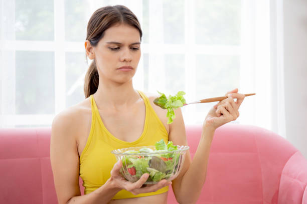 istock Young caucasian woman sitting on sofa eating vegetable salad while feeling dislike and expression disgusted, woman emotion frustrated with anorexia vegetarian and hate, nutrition food concept. 1434584367