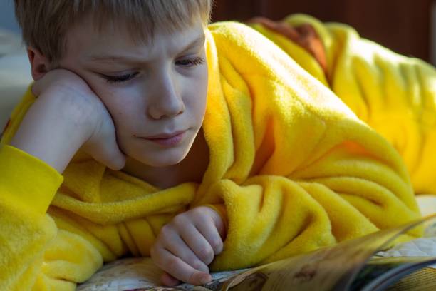 istock boy lying in bed with a book. child reading home education 1434586290