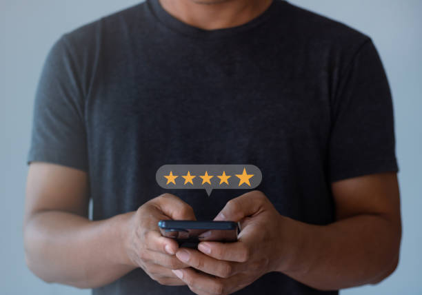 istock Man hand using smartphone with popup five star icon for feedback review satisfaction service on the online application, Customer service experience and business satisfaction survey. 1434586436