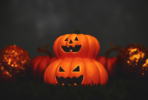 Grinning Jack O'lanterns in grass at night. Space for text