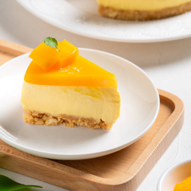 istock Delicious glazed mango no baked cheese cake with fresh diced mango pulp topping on bright table background. 1434589965