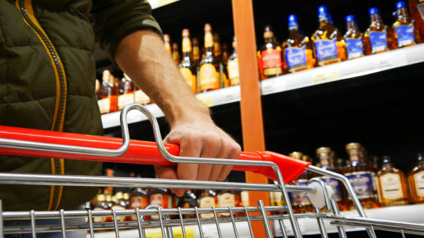 Close-up of a male buyer's hand pushing a shopping trolley in a liquor store stock photo