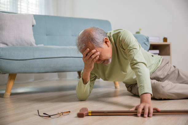 istock Asian senior man falling down lying on floor at home alone with wooden walking stick 1434595019