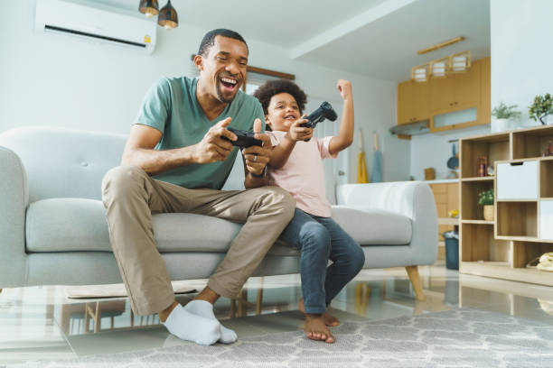 padre e figlio africani che giocano ai giochi per console - family sofa men sitting foto e immagini stock