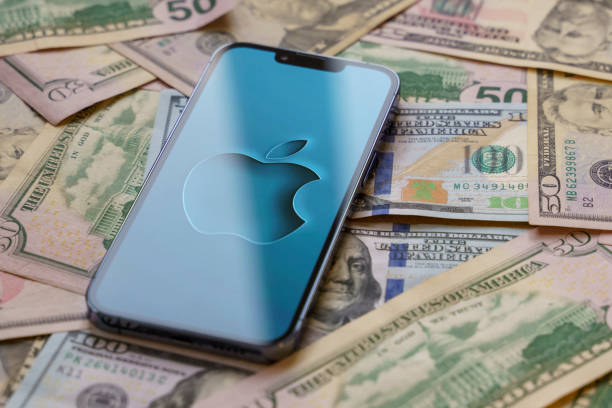 apple iphone 13 pro smartphone with apple logo on the screen stands over us dollar banknotes - iphone trading stock market finance imagens e fotografias de stock