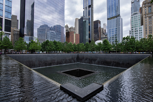 June 18, 2022: Wide angle view of the Ground Zero 9/11 Memorial in Lower Manhattan, New York City, USA. New York architecture in the background.