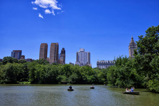 People in rowboats on lake of Central Park during summer day.