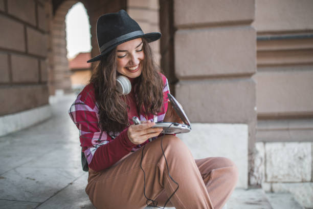 una giovane donna felice trascorre la giornata all'aperto, ascoltando musica tramite un mini lettore di dischi - cd player foto e immagini stock