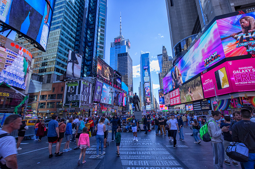 Time Square in New York City, covered with illuminated billboards with crowd of tourists on the streets.