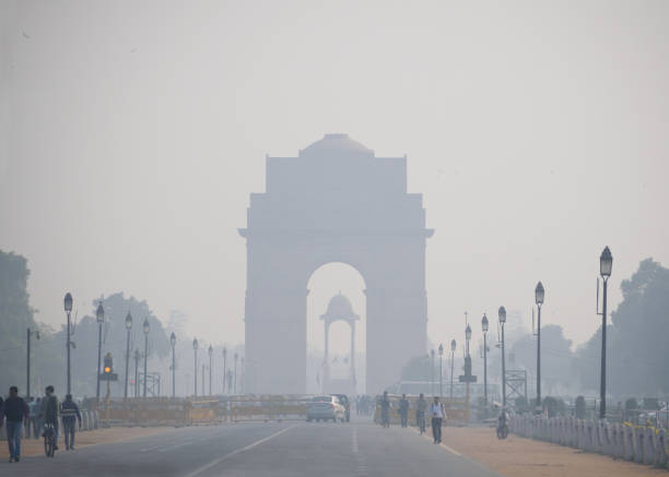 Delhi, India - November 21, 2017: Daily commuters walking in the road in front of  India gate in New Delhi covered in smog.