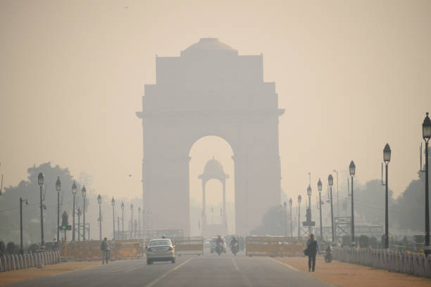 Delhi, India - November 21, 2017: Daily commuters walking in the road in front of  India gate in New Delhi covered in smog.