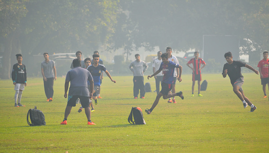 Delhi, India - November 21, 2017: People playing football in a park amidst smog.