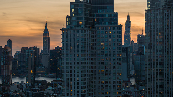 Long Island City waterfront with Empire State Building seen behind in Midtown Manhattan over the East River at sunset.