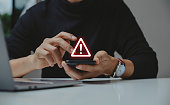 Businessman using smartphone with warning sign.