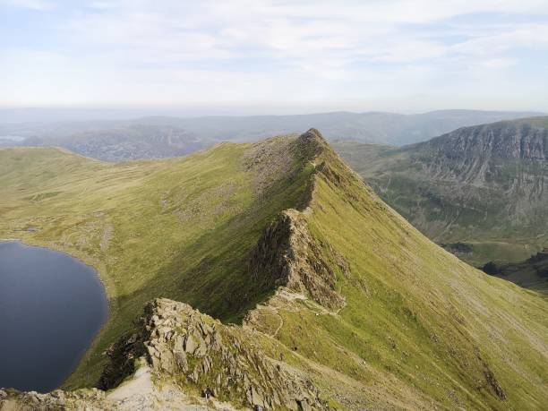 Striding Edge mountain peak near a lake with a blue sky in the background, Lake District, England The Striding Edge mountain peak near a lake with a blue sky in the background, Lake District, England striding edge stock pictures, royalty-free photos & images