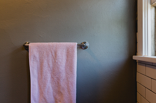 A pink bath towel in a bathroom hanging on the towel rack. Copy space available.