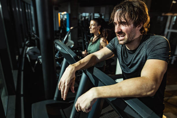 istock Exhausted male athlete taking a break from exercising on a treadmill in a gym. 1434619913