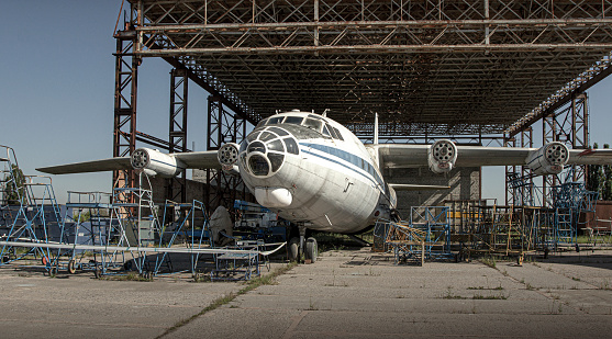 an old plane on the ground, in an old hangar