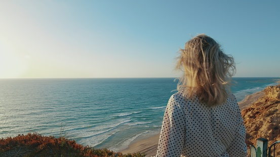 Woman calmly stands in front of the sea