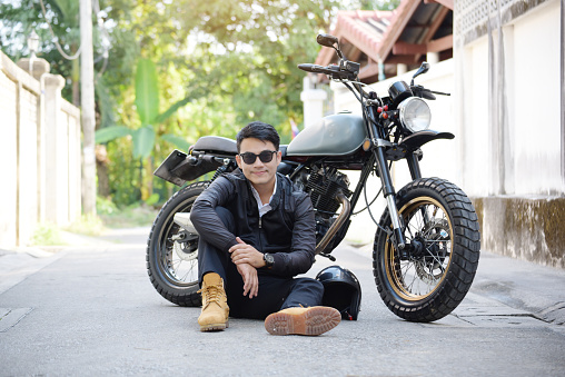 Asian man motorbike in black leather jacket travel rider trip. Handsome Men wear sunglass outdoor lifestyle freedom rider. Men trendy hipster cool person. Young asian man hobby ride with motor bike