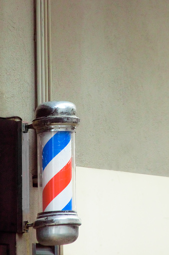 Barbershop old fashioned symbol seen in the street. Red and blue moving cylinder with copy space available on the upper part of the image. Galicia, Spain.