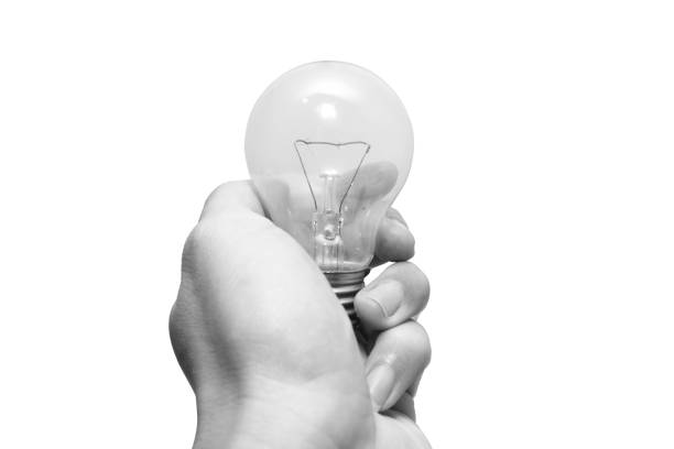istock closeup black and white man hand holding old tungsten light bulb isolated on white background 1434627651